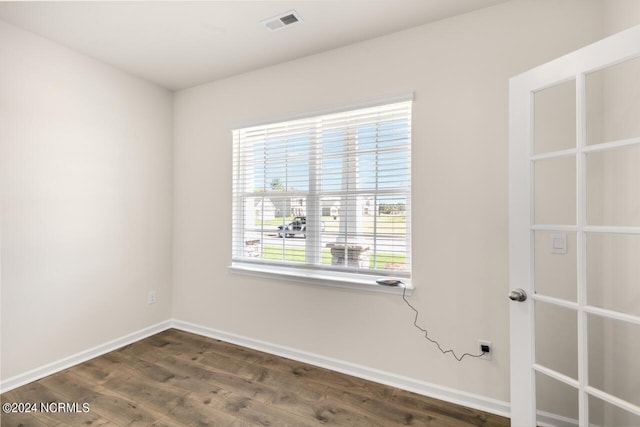 unfurnished room featuring dark wood finished floors, baseboards, and visible vents