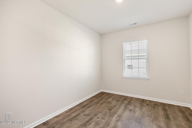 empty room with visible vents, baseboards, and dark wood finished floors