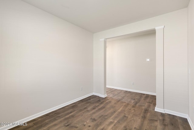 spare room with baseboards and dark wood-style floors