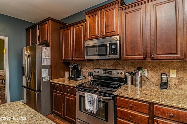 kitchen with light stone countertops, backsplash, appliances with stainless steel finishes, and dark wood-style flooring