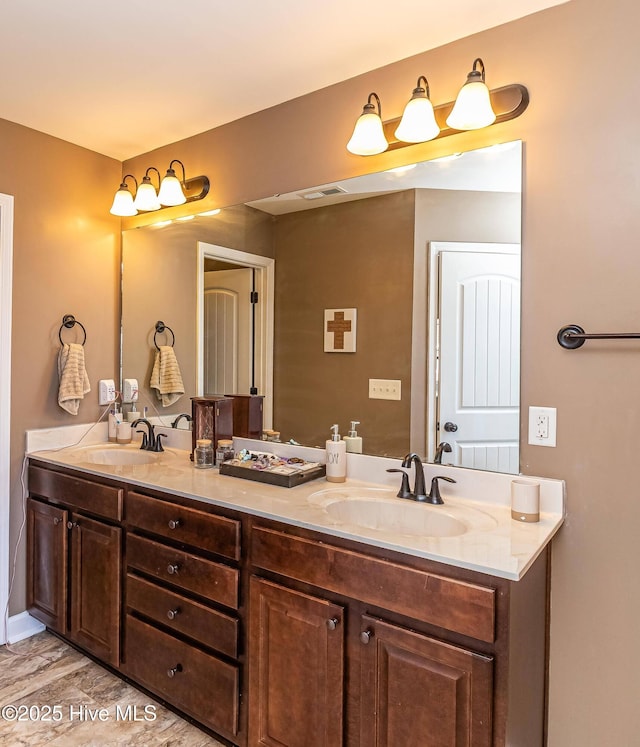 bathroom with double vanity, visible vents, and a sink