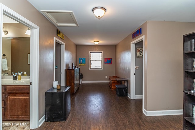 interior space featuring a sink, baseboards, attic access, and dark wood-style flooring