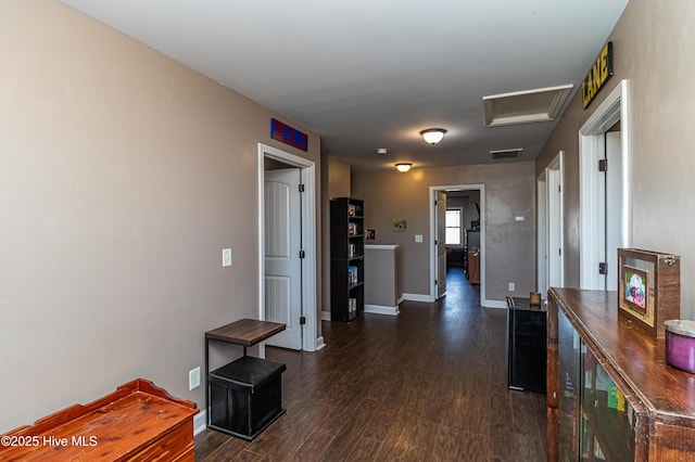 hallway with visible vents, baseboards, dark wood-type flooring, and attic access