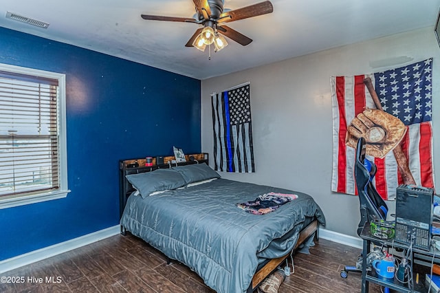 bedroom with ceiling fan, wood finished floors, visible vents, and baseboards