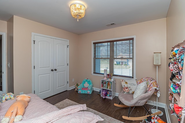 bedroom with wood finished floors, visible vents, a closet, and baseboards