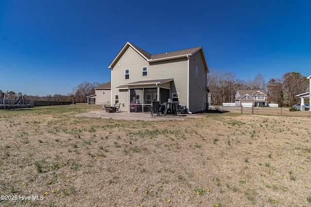 rear view of property featuring a trampoline, a fenced backyard, a yard, and a sunroom