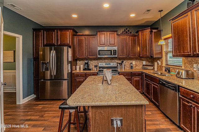 kitchen featuring visible vents, a sink, appliances with stainless steel finishes, a kitchen breakfast bar, and backsplash