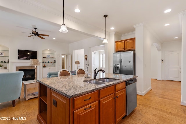 kitchen featuring arched walkways, ceiling fan, a sink, appliances with stainless steel finishes, and light wood-type flooring