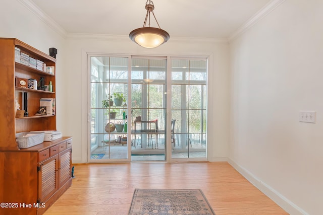 entryway with plenty of natural light, light wood finished floors, and ornamental molding