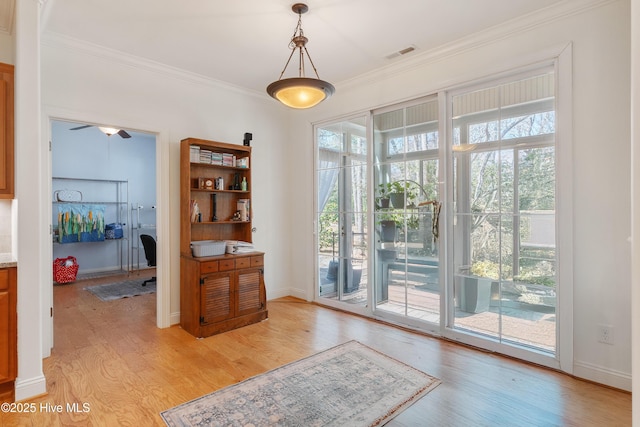 doorway to outside with visible vents, light wood-style flooring, baseboards, and ornamental molding