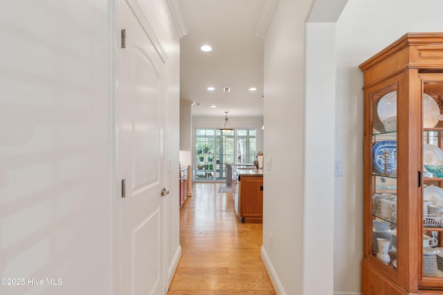 hallway with recessed lighting, light wood-type flooring, baseboards, and crown molding