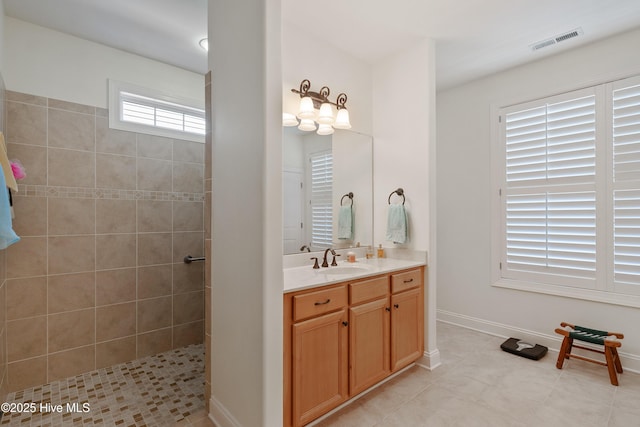 full bathroom with visible vents, baseboards, tile patterned flooring, tiled shower, and vanity