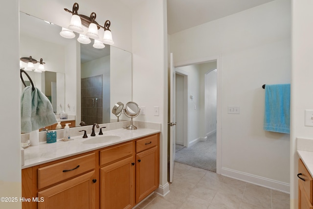 full bath with vanity, tile patterned floors, baseboards, and tiled shower