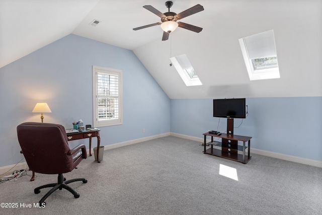 office space with a ceiling fan, visible vents, carpet, baseboards, and vaulted ceiling with skylight