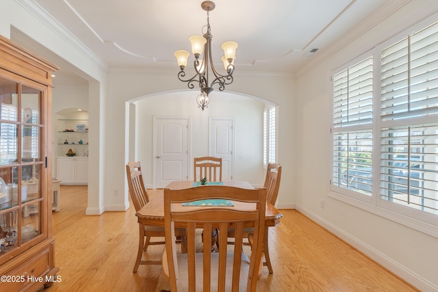 dining room featuring a notable chandelier, light wood-style floors, baseboards, and ornamental molding