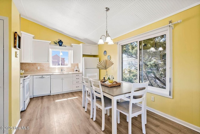 dining area with a notable chandelier, baseboards, light wood-style floors, and vaulted ceiling