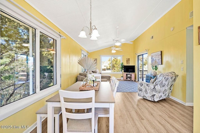 dining space featuring light wood finished floors, visible vents, baseboards, vaulted ceiling, and ceiling fan with notable chandelier