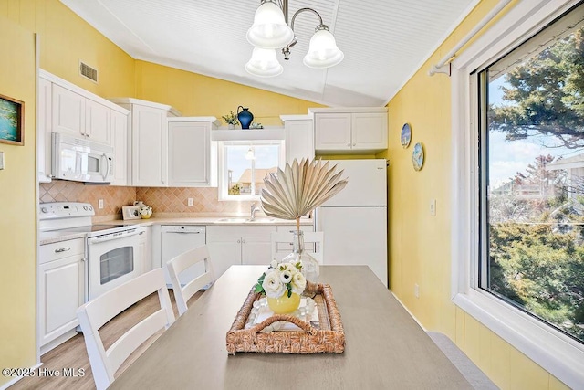 kitchen featuring visible vents, tasteful backsplash, white appliances, white cabinets, and vaulted ceiling