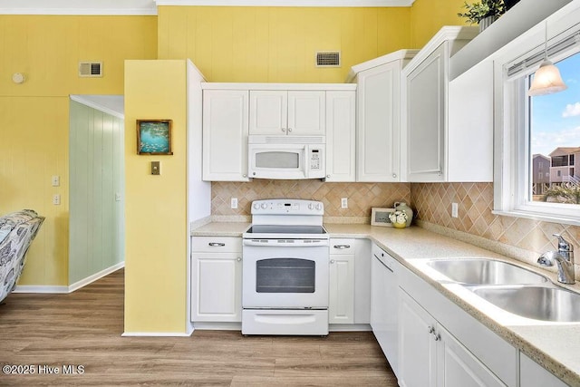 kitchen featuring a sink, visible vents, white appliances, and white cabinets