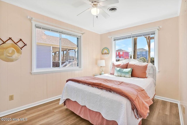 bedroom with visible vents, wood finished floors, baseboards, and ornamental molding