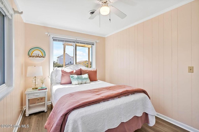 bedroom with baseboards, crown molding, ceiling fan, and wood finished floors