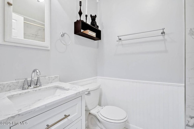 full bathroom with vanity, walk in shower, toilet, and wainscoting