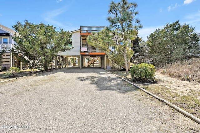 coastal home featuring a carport, gravel driveway, and stairs