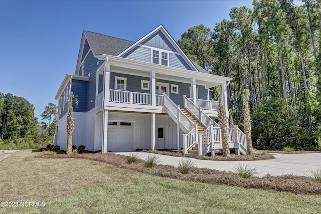 coastal inspired home featuring stairway, covered porch, concrete driveway, a garage, and board and batten siding