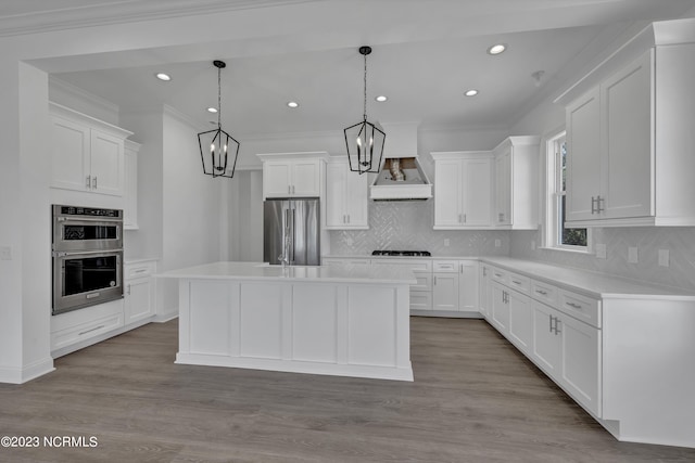 kitchen with a chandelier, light countertops, custom range hood, ornamental molding, and appliances with stainless steel finishes