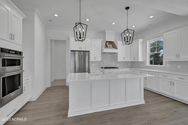 kitchen with custom exhaust hood, a chandelier, stainless steel appliances, and light countertops