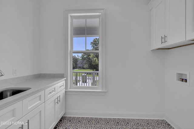 laundry area featuring a sink, baseboards, cabinet space, and washer hookup