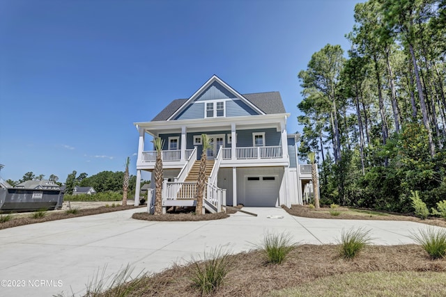 coastal home with stairway, a porch, driveway, and a garage