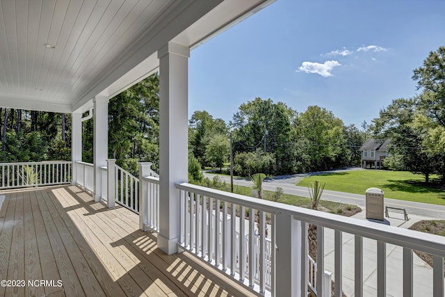 wooden deck featuring covered porch and a yard