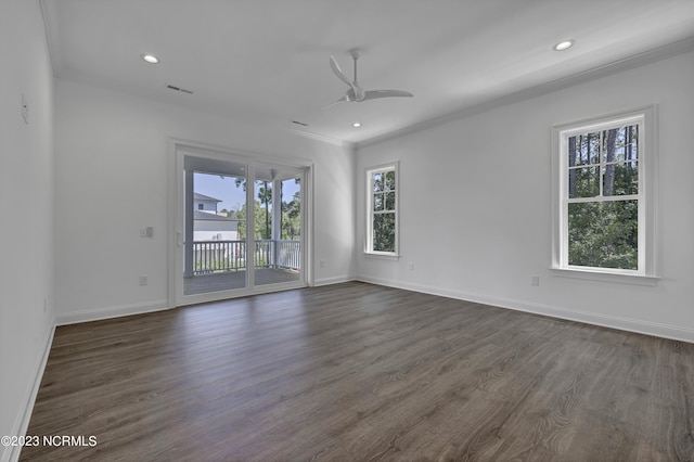 empty room featuring dark wood finished floors, visible vents, a ceiling fan, and ornamental molding