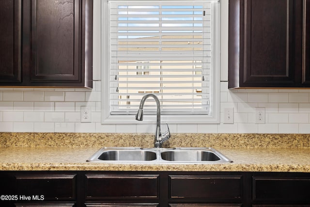 kitchen with a sink, tasteful backsplash, and dark brown cabinets