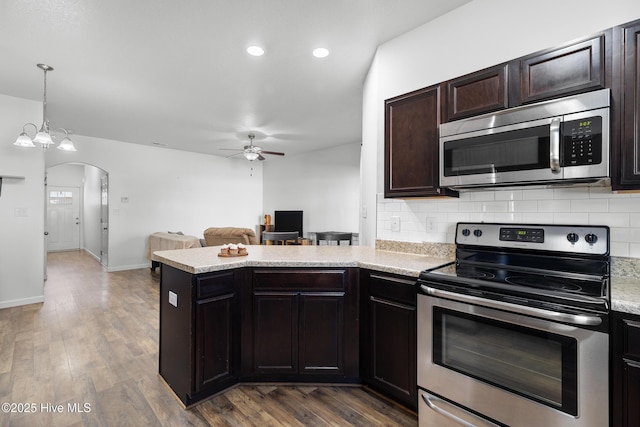 kitchen with a ceiling fan, open floor plan, arched walkways, appliances with stainless steel finishes, and a peninsula