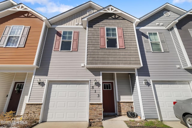 townhome / multi-family property featuring stone siding, driveway, board and batten siding, and an attached garage