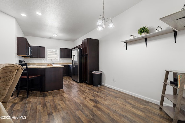 kitchen with stainless steel appliances, light countertops, dark wood-type flooring, dark brown cabinets, and a kitchen breakfast bar