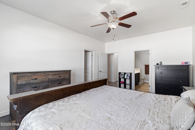 bedroom featuring visible vents, ensuite bathroom, wood finished floors, baseboards, and ceiling fan