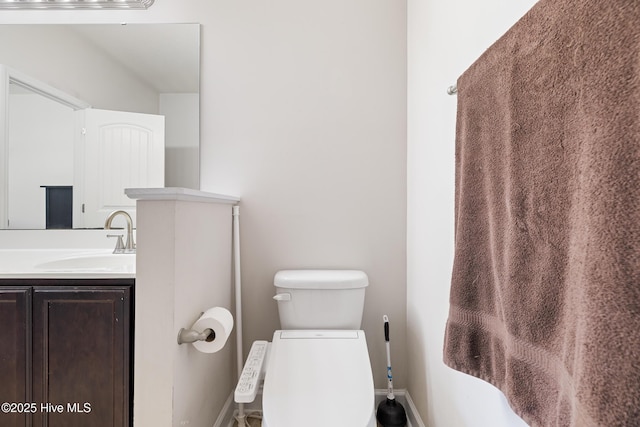 bathroom featuring baseboards, toilet, and vanity