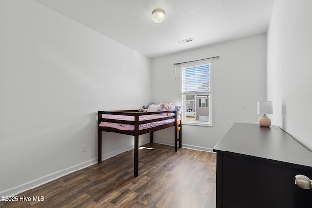 bedroom with visible vents, baseboards, and dark wood-style flooring