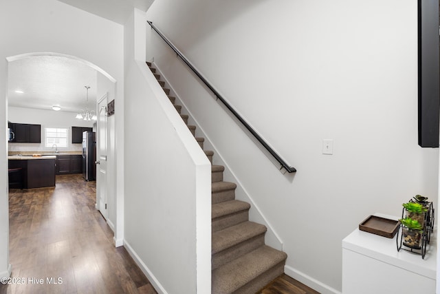 stairs with baseboards, arched walkways, and wood finished floors