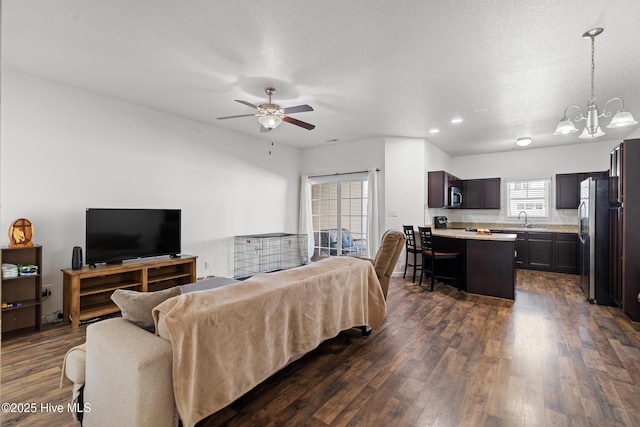 living room featuring dark wood-type flooring and ceiling fan with notable chandelier