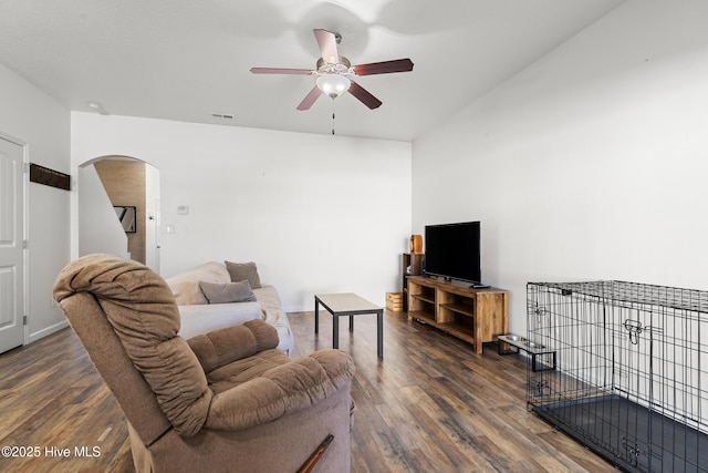 living area with arched walkways, visible vents, ceiling fan, and wood finished floors