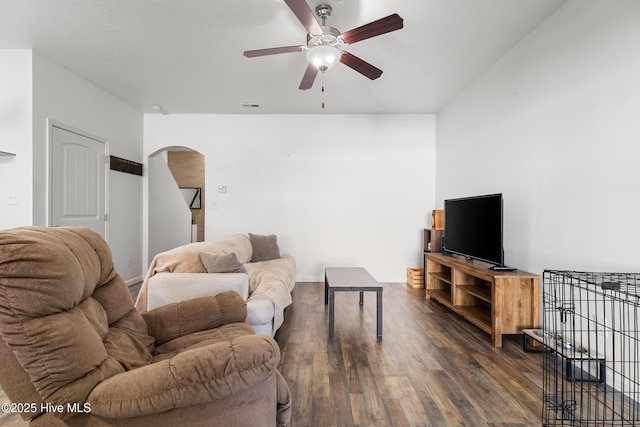 living area featuring visible vents, arched walkways, baseboards, ceiling fan, and dark wood-style flooring