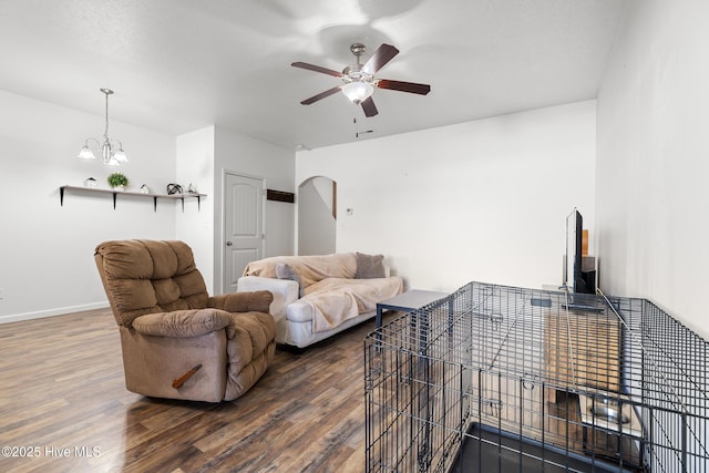 living area featuring arched walkways, baseboards, a ceiling fan, and wood finished floors