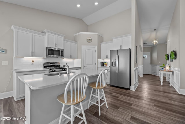 kitchen with a kitchen island with sink, a sink, stainless steel appliances, light countertops, and white cabinetry