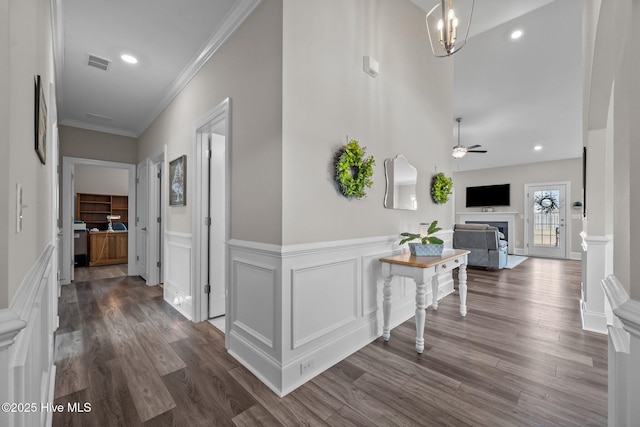 hall featuring dark wood finished floors, visible vents, wainscoting, and crown molding