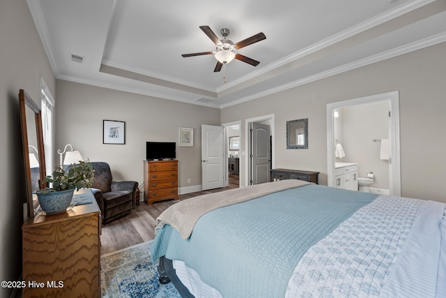 bedroom featuring visible vents, ornamental molding, a tray ceiling, and wood finished floors