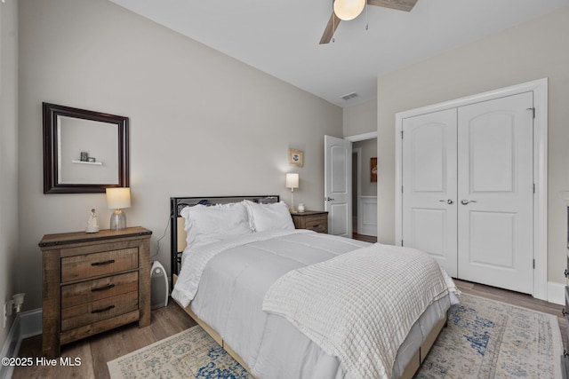 bedroom featuring visible vents, baseboards, wood finished floors, a closet, and a ceiling fan